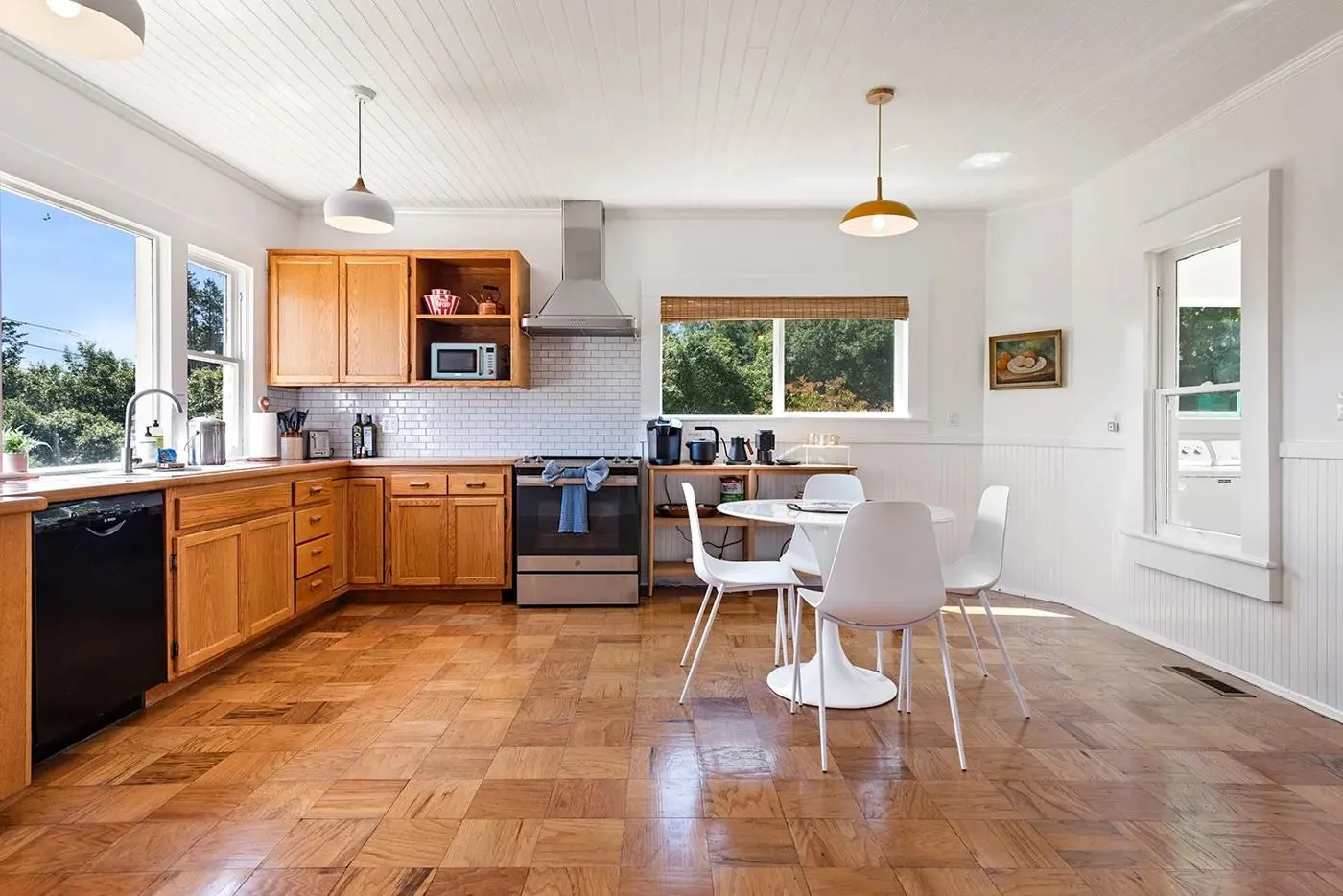 Sunny kitchen with parquet floors and a white tulip table