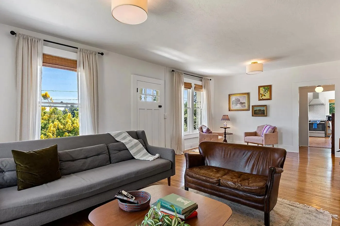 Living room with leather loveseat, gray sofa and framed landscapes