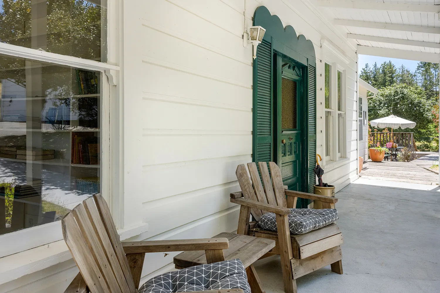 The original scalloped green door on the front porch, with two Adirondack chairs
